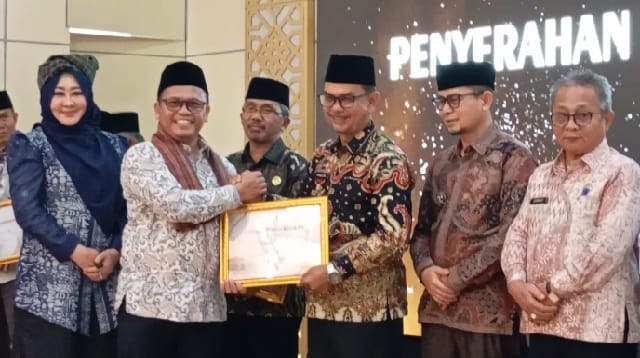 Sekretaris Jenderal (Sekjen) Kementerian Haji dan Umrah (Kemenhan), Teguh Dwi Nugroho menyerahkan Piagam Penghargaan kepada Bupati Pasaman, H Parulian Dalimunthe atas penyelenggaraan ibadah haji 1447 H tahun 2027 di Asrama Embakasi Padang, Jum'at (31/7). (MR)